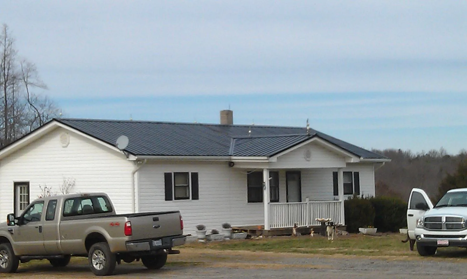 Finished dark metal roof on a white ranch home with work trucks parked in Dixon